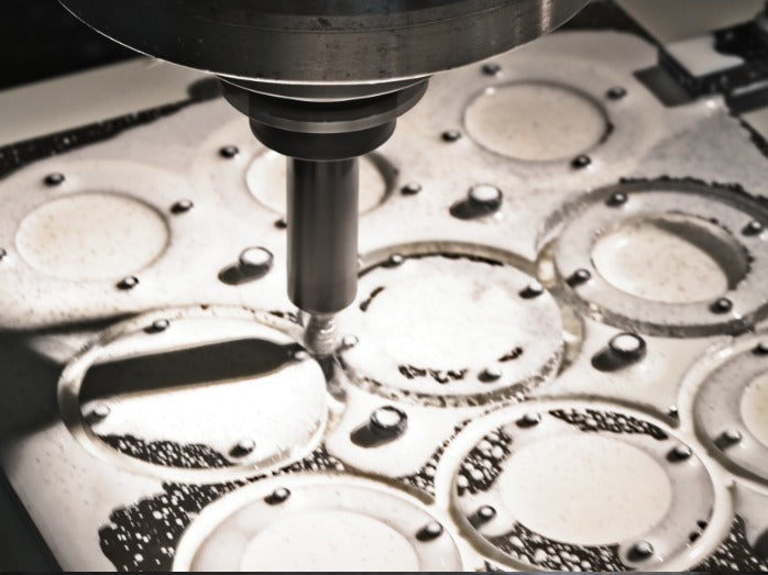 A CNC machine precisely cuts circular patterns into a metal sheet. The scene conveys precision engineering, with metal shavings scattered around.